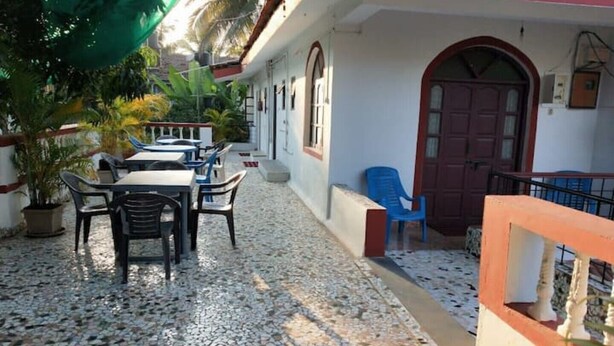 A courtyard with a tiled floor, outdoor seating, potted plants, and a red door. - Alexmarie Holiday Home  (5) nr Candolim Beach  (Bardez Candolim)