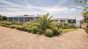 A coastal building with a gravel pathway, surrounded by greenery and a clear sky. - Residence Pierre & Vacances Audierne le Phare de Trescadec (Audierne)