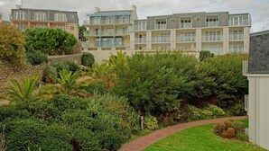 A multi-story residential building with balconies and a well-maintained garden. - Residence Pierre & Vacances Audierne le Phare de Trescadec (Audierne)