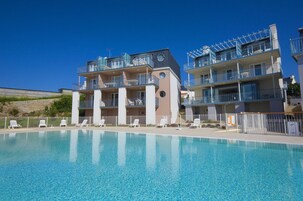 Un hotel con piscina, diversi balconi e un cielo azzurro limpido.