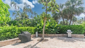 A paved outdoor area with a tree, a covered grill, and a planter. - ISLAND MANOR Unit K4- 2 BR/1 BA - NEWLY REMODELED (Marco Island)