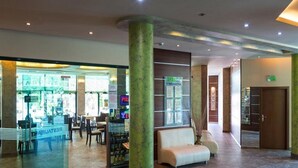 Un vestíbulo de hotel con una zona de estar, un bar de aperitivos y una recepción.