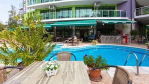 Un hotel con piscina, zona de estar al aire libre y bar.