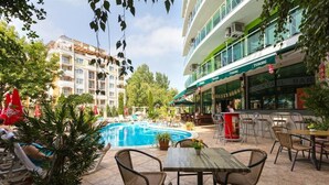 Zona de piscina al aire libre con sillones de descanso y un bar.