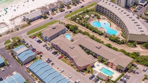 An aerial view of a coastal hotel with multiple buildings, a beach, and a swimming pool.