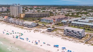 A coastal resort area with beachfront properties, a beach with umbrellas, and a bridge in the distance.