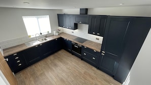 Una cocina moderna con armarios oscuros, encimera de madera y horno empotrado.