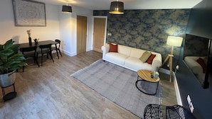 Una sala de estar moderna con sofá, mesa de comedor, sillas y una alfombra estampada.