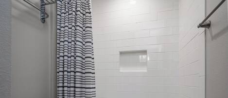A bathroom with a white bathtub, a toilet, and a shower curtain with a black and white pattern.
