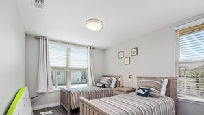 A bedroom with two beds, a window with blinds, a radiator, and a ceiling light. - Little's Toasty Coasty by Miss Kitty’s (Rockport)