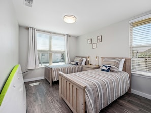A bedroom with two beds, a window with blinds, a radiator, and a ceiling light. - Little's Toasty Coasty by Miss Kitty’s (Rockport)