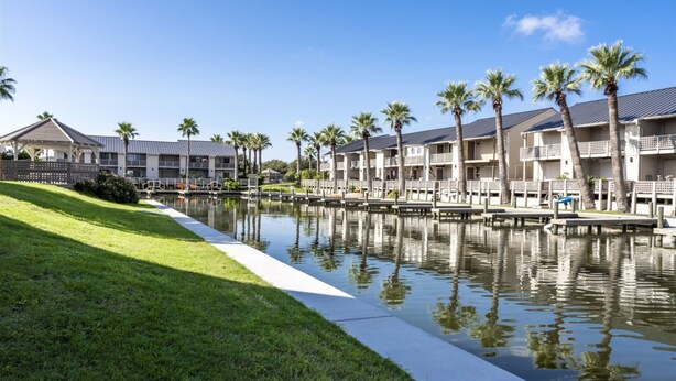 A waterfront hotel with multiple-story buildings, a canal, and palm trees. - Little's Toasty Coasty by Miss Kitty’s (Rockport)