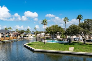 A residential area with a swimming pool, palm trees, and houses. - Little's Toasty Coasty by Miss Kitty’s (Rockport)