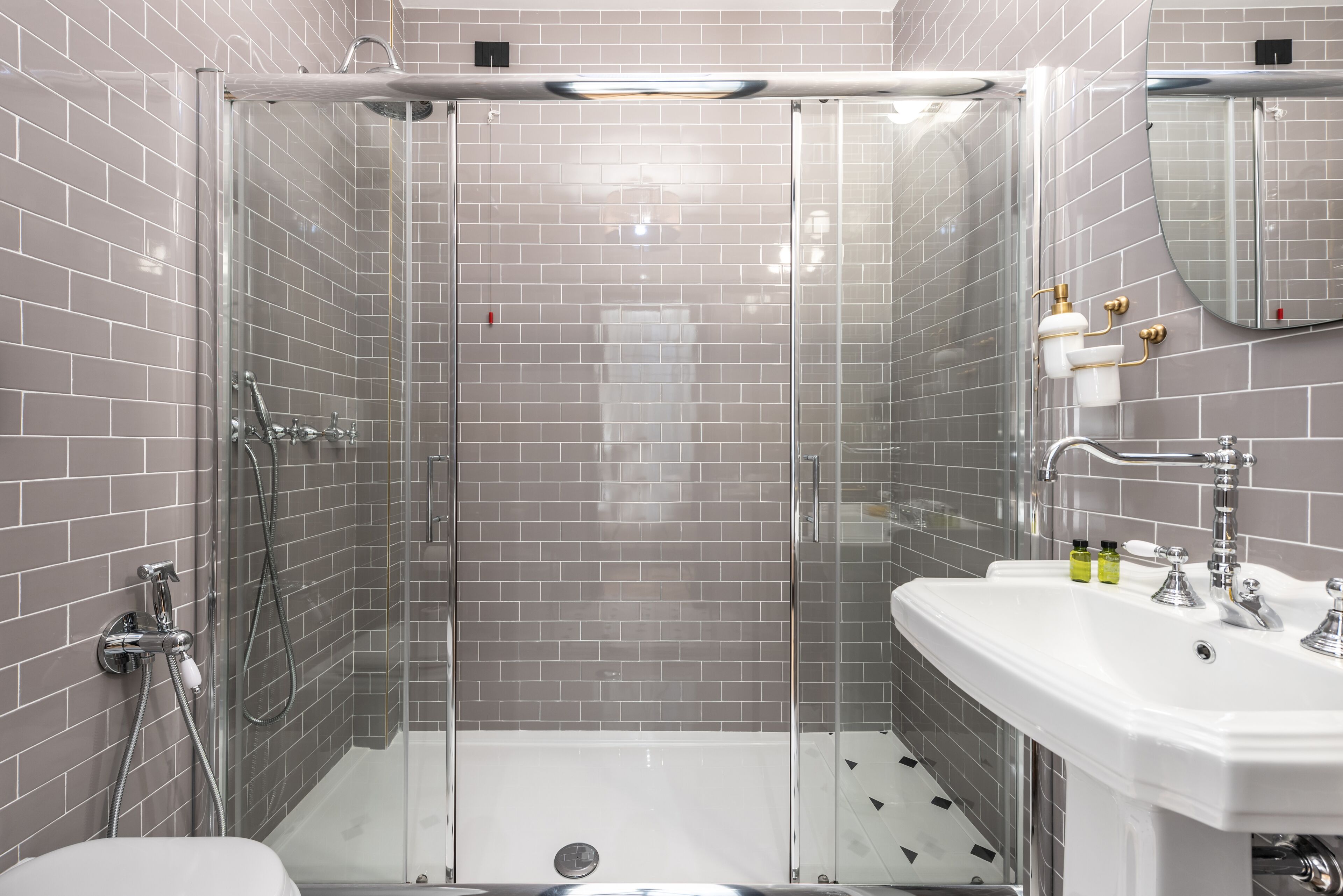 A modern bathroom with a glass-enclosed shower, a white sink, and a mirror.