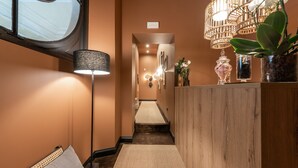 Un couloir avec un comptoir d’accueil en bois, une lampe et une plante.