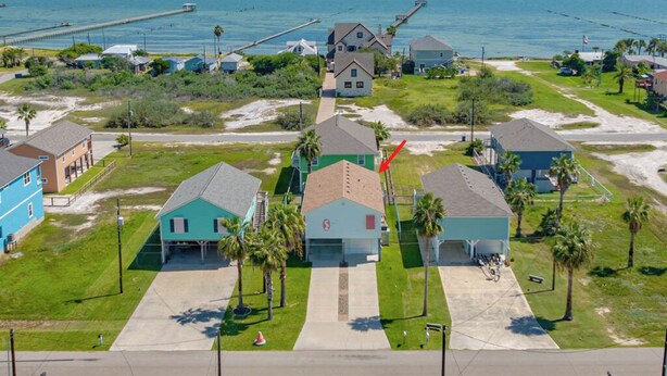 A coastal residential area with houses, a pier, and a clear view of the ocean. - Sandy Pants Beach House by Miss Kitty’s (Rockport)
