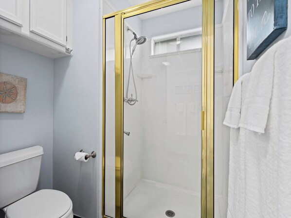 Une salle de bain avec une douche à parois de verre, des toilettes et une serviette accrochée au mur.