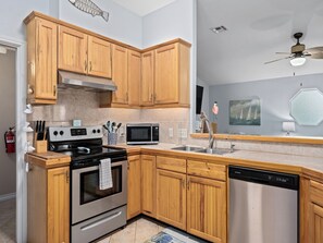 A modern kitchen with wooden cabinets, stainless steel appliances, a microwave, and a dishwasher.