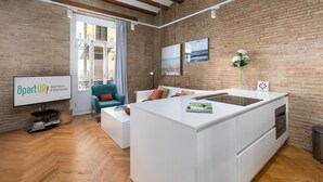 Un salon moderne avec un îlot central blanc, un canapé et un téléviseur diffusant des images d'appartements et proposant des expériences proposées par « apartUP! ».