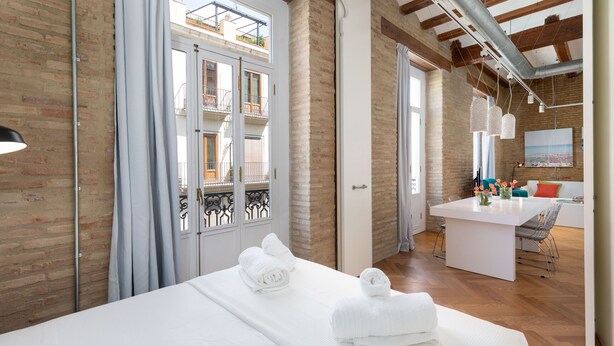 Une chambre d’hôtel avec un lit, un petit coin cuisine et une vue sur le balcon extérieur.
