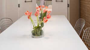 Une chambre d’hôtel moderne avec une table blanche, un vase de fleurs et un lit doté d’une tête de lit.