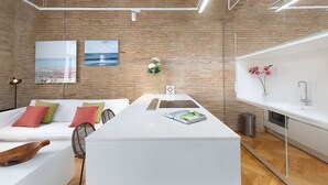 Un espace de vie moderne avec un mur en briques, des meubles blancs et des œuvres d’art.
