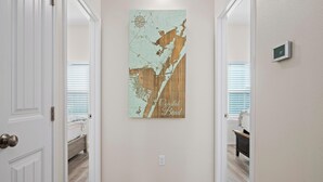 Un couloir doté d’un plancher en bois, d’un luminaire fixé au mur et d’une carte encadrée intitulée « Coastal Bend ».