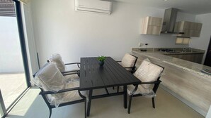 A modern kitchen with a built-in stove, a sink, and wooden cabinets. There is a dining table with chairs and a potted plant. - Alondra 3304 ByTrvl2hm (Mazatlán)