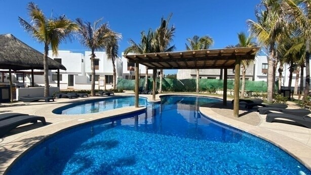 A swimming pool with lounge chairs and a pergola, surrounded by palm trees and a building. - Alondra 3304 ByTrvl2hm (Mazatlán)