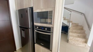 A compact kitchen with a refrigerator, microwave, oven, and a small pantry. - Alondra 3304 ByTrvl2hm (Mazatlán)