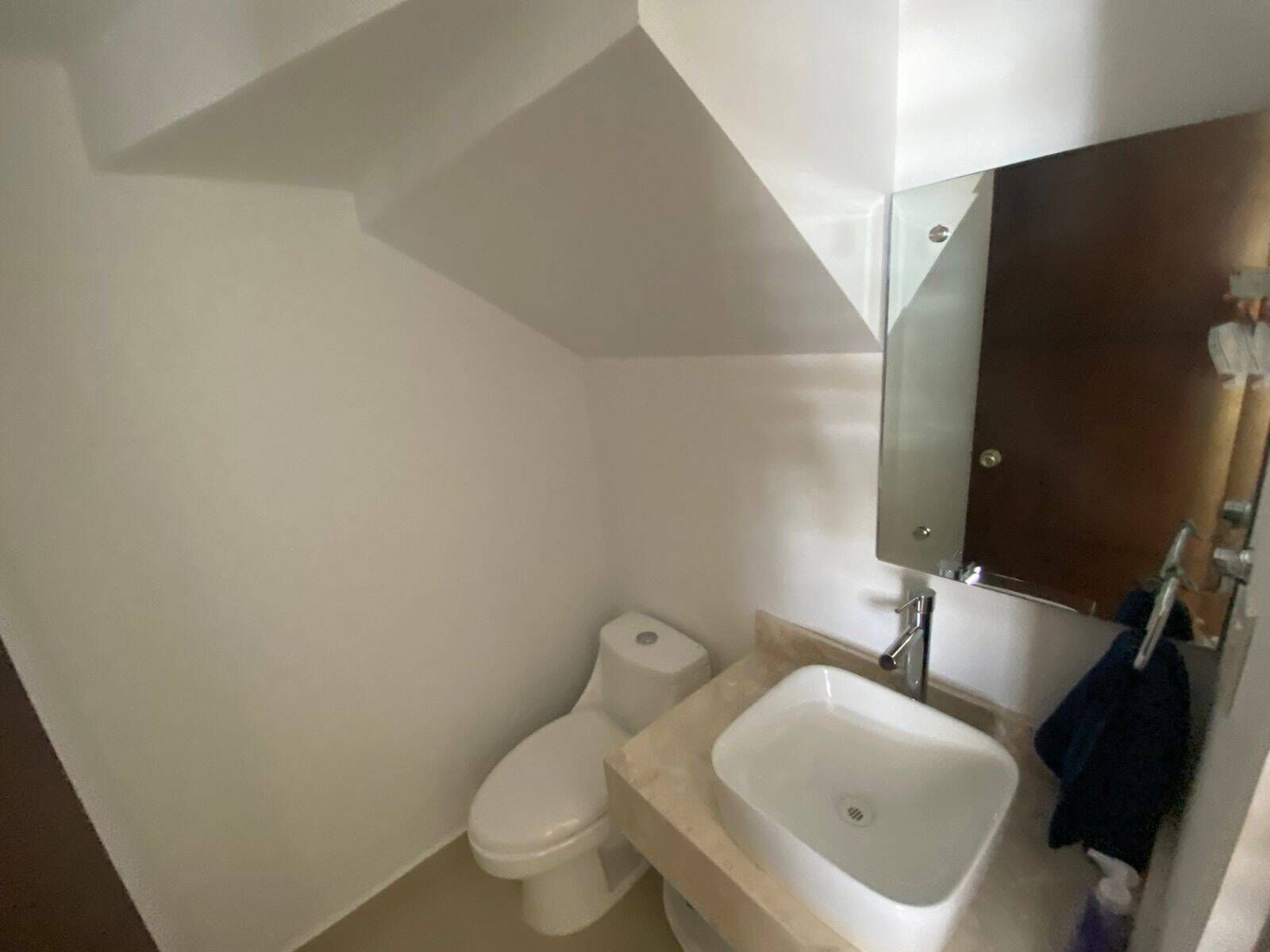 A small bathroom with a toilet, sink, and mirror.