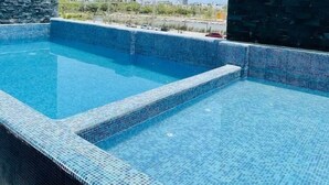 A rooftop swimming pool with clear blue water, surrounded by stone and glass walls, offering a view of the cityscape. - CONDOS ONE ByTrvl2hm & Mazatlan Regency (Mazatlán)