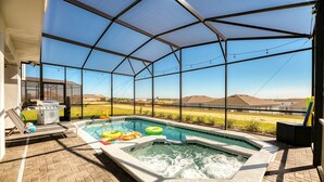 Piscina exterior techada con jacuzzi, rodeada por una estructura metálica y vistas a colinas distantes.