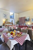 A dining area with checkered tablecloths, breakfast plates, and a television on the wall.
