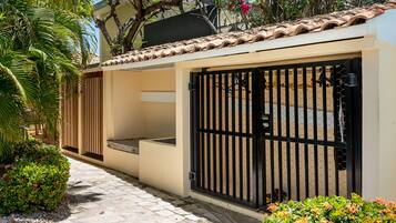 Uma casa moderna com telhado em telhas, portão e pequena varanda.