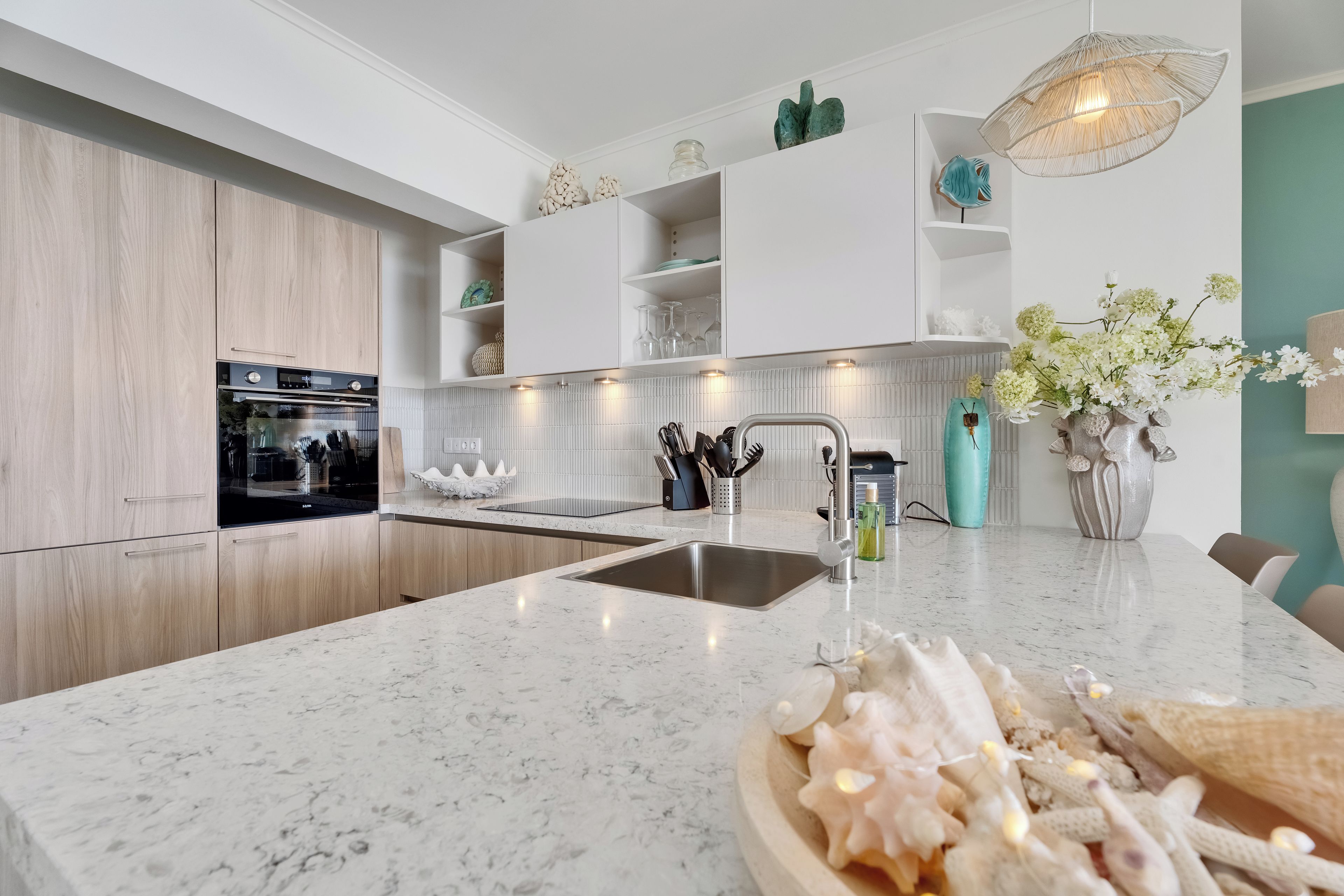 A modern kitchen with a central island, stainless steel sink, and a built-in oven.