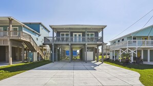 Een rij strandappartementen met balkons, een centrale gangpad en een heldere lucht.