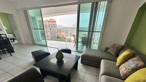 Ein modernes Wohnzimmer mit einer Couch, einem Couchtisch und Blick auf eine Skyline durch große Fenster.