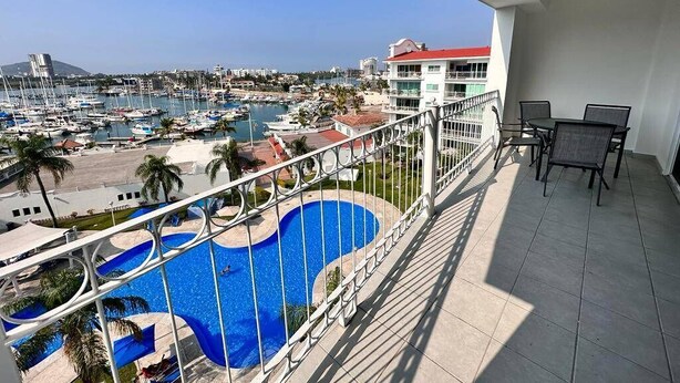 Ein Balkon mit Blick auf eine Marina, ein Schwimmbad und ein Gebäude mit rotem Dach.