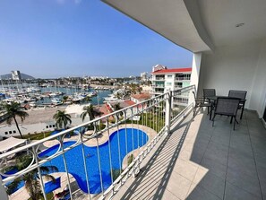 A balcony with a view of a marina, a swimming pool, and a building with a red roof. - Condos Puesta DS ByTrvl2hm (Mazatlán)