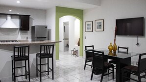 Eine moderne Küche mit Granit Arbeitsplatte, dunklen Schränken und einer eingebauten Mikrowelle. Es gibt eine Essecke mit einem Glastisch und vier Stühlen.