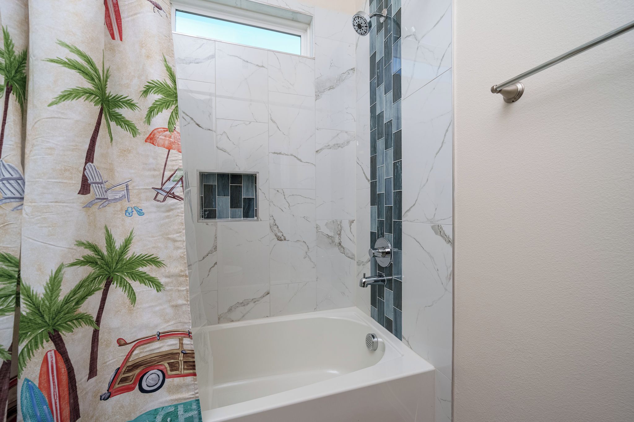 Une salle de bain avec une baignoire, une douche avec une porte en verre et un porte-serviettes.