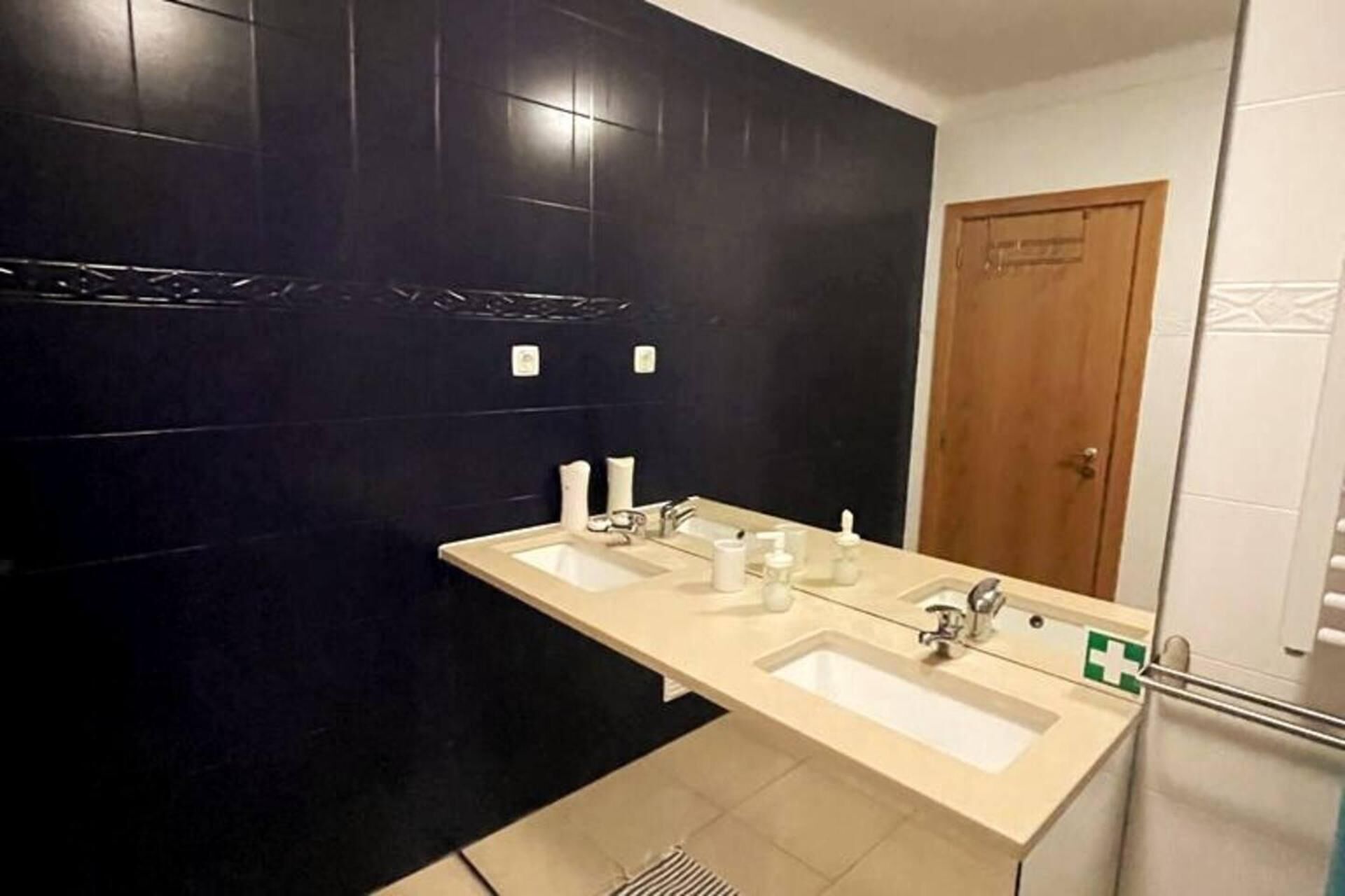 A bathroom with two sinks, a mirror, and a door.