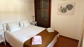 A hotel room with a bed, a nightstand, a lamp, a window, and a wall decoration. - Omontinho - 4-bed House With Pool in Melides (Grandola)