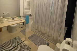 A bathroom with a sink, toilet, and shower curtain.