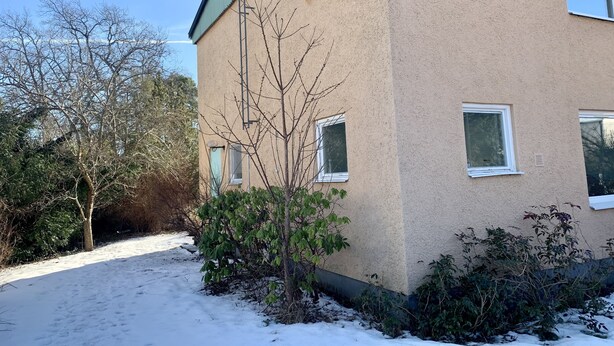 A two-story building with a beige exterior, multiple windows, and a green roof. - Apartment in Hagersten Stockholm (Hägersten)