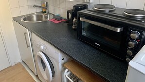 A compact kitchen with a washing machine, a microwave, and a sink. - Apartment in Hagersten Stockholm (Hägersten)