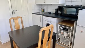 A compact kitchen with a washing machine, a microwave, and a sink. - Apartment in Hagersten Stockholm (Hägersten)