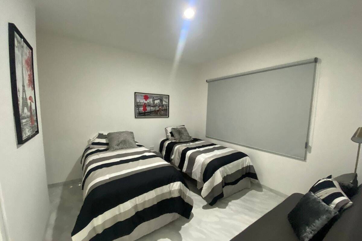 Un dormitorio con dos camas, un ventanal grande y una pantalla para proyector.