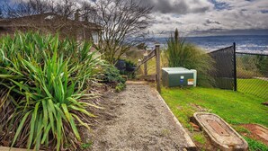 A gravel path leading to a wooden staircase, surrounded by greenery and a fence overlooking a distant landscape. - Valley Views Apartment  (Happy Valley)
